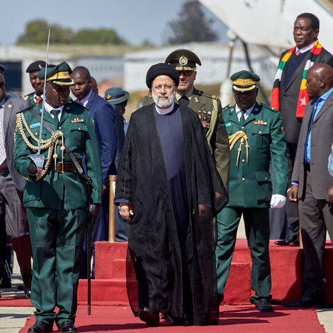 Iranian President Ebrahim Raisi (C) inspects the guard of honor upon his arrival for a state visit at the Robert Gabriel Mugabe International Airport in Harare on July 13, 2023. 