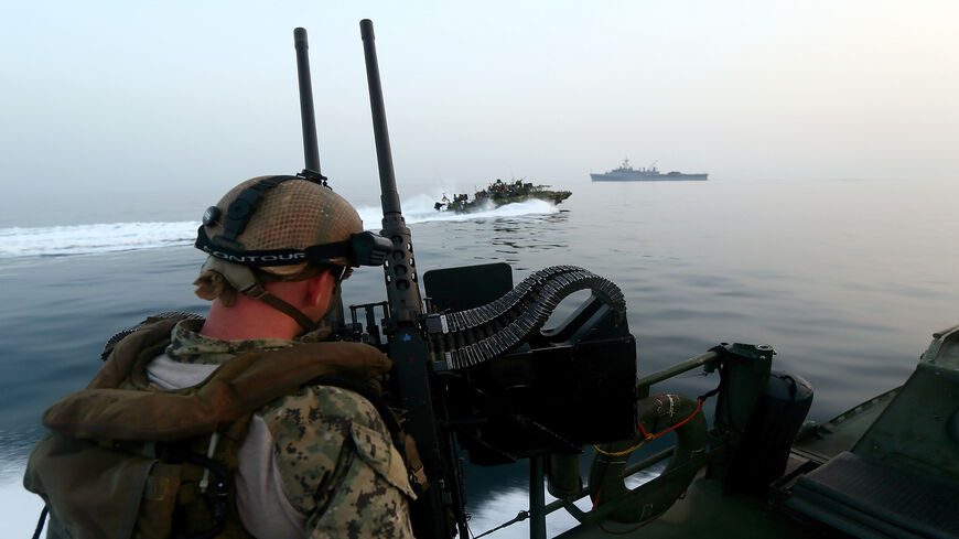 A US Navy personnel mans a heavy machine gun as he watches a Riverine Command Boat (C) cruising past the USS Ponci in the Arabian Sea, on the first day of the the biggest mine countermeasures exercise in the Arabian Gulf, May 13, 2013.