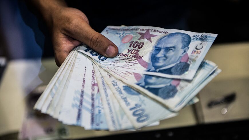 A teller holds Turkish lira banknotes at a currency exchange office in Istanbul, Aug. 13, 2018.