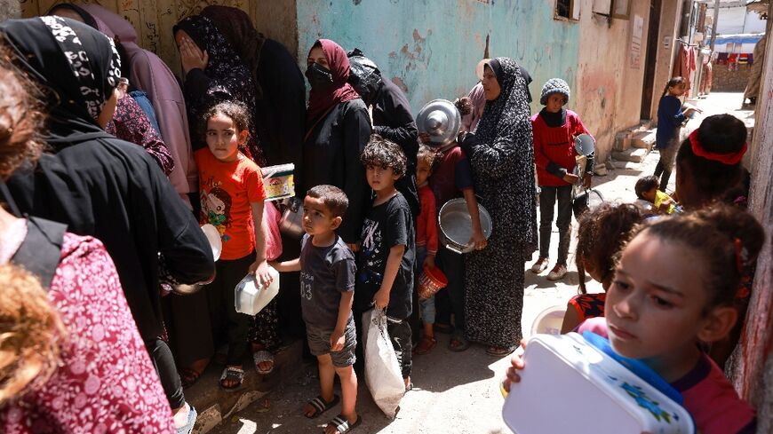 Displaced Palestinian children line up to receive food in Rafah