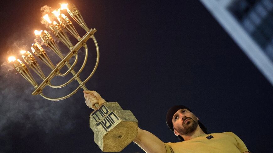 A protester carries a menorah as relatives and supporters of Israeli hostages in Gaza demonstrate  in Tel Aviv