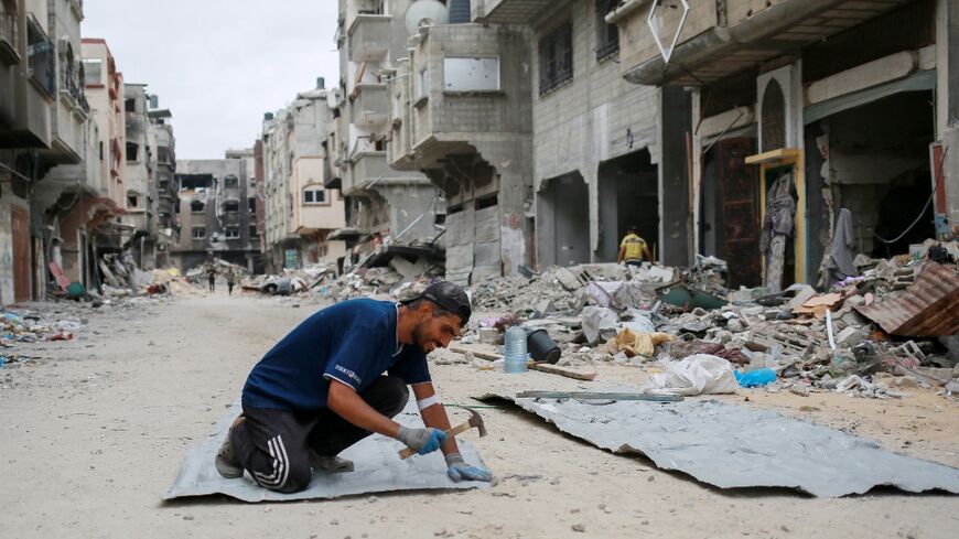 In Khan Yunis, southern Gaza, a Palestinian man fixes tin sheets used for temporary sheltering -- most of Gaza's population has been uprooted by the war