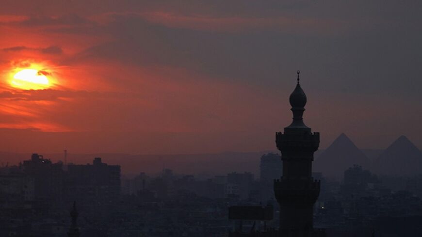 The sun sets on the minarets and the Great Pyramids of Giza (R) in Old Cairo December 31, 2013. REUTERS/Amr Abdallah Dalsh  (EGYPT - Tags: CITYSCAPE SOCIETY TPX IMAGES OF THE DAY) - RTX16Y9H