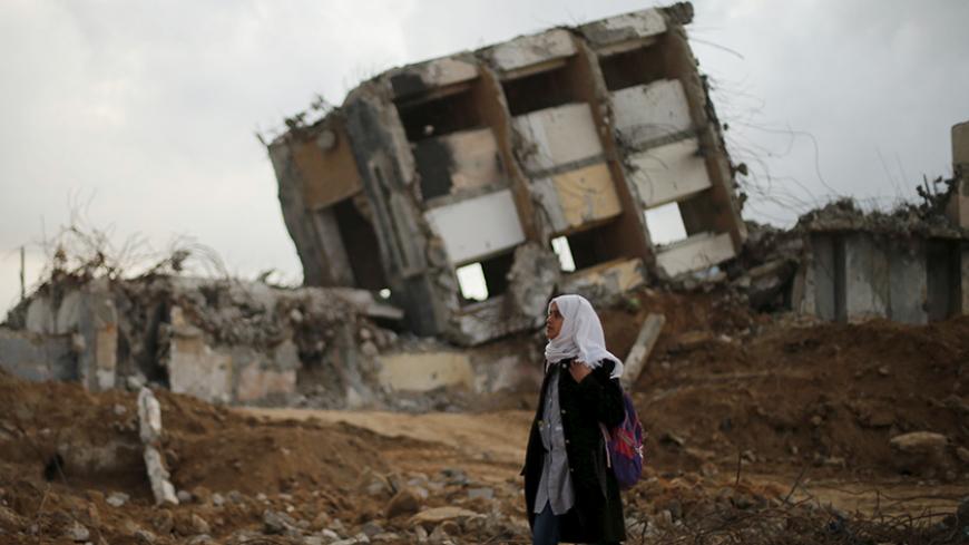 A Palestinian schoolgirl walks past the remains of a house, destroyed during 2014 war, as she returns to her home on a winter day in the northern Gaza Strip February 10, 2016. REUTERS/Mohammed Salem   - RTX26D1S