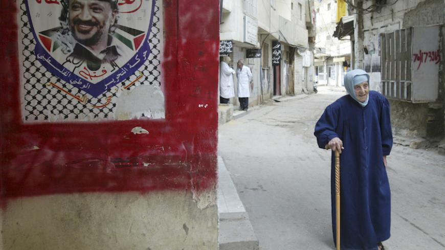 A Palestinian woman walks past an image of Yasser Arafat in Shatila refugee camp near Beirut May 23, 2007. The Lebanese army is trying to crush Fatah al-Islam, a militant group led by a Palestinian but with little or no support among Lebanon's Palestinian refugee population of 400,000. Dozens of people have died in three days of fighting.  REUTERS/Sharif Karim (LEBANON) - RTR1Q090
