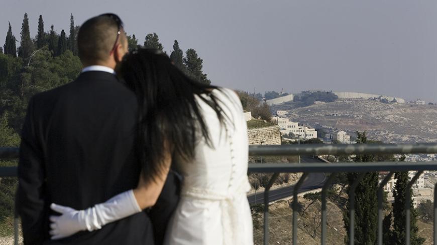 An Israeli Arab couple watches the view, which includes Israel's controversial separation barrier (top R), during the photo shooting before their wedding in Jerusalem on November 26, 2009. Israel's offer to freeze settlement building in the occupied West Bank for 10 months does not go far enough, Russia's foreign ministry said, urging a full stop to construction. AFP PHOTO/JONATHAN NACKSTRAND (Photo credit should read JONATHAN NACKSTRAND/AFP/Getty Images)