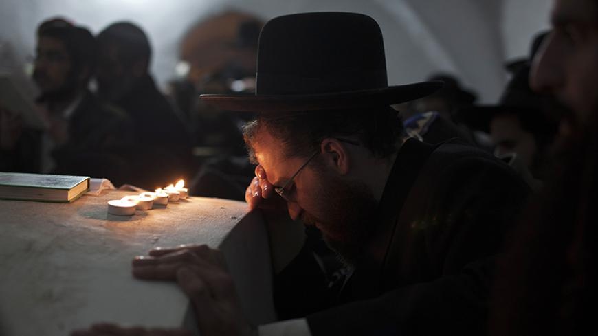 An Ultra-Orthodox Jewish man prays next to candles in the Tomb of Caleb Ben Yefuneh in the West Bank village of Kifl Hares, near the Jewish settlement of Ariel, January 5, 2012. The Israeli army late on Wednesday night allowed hundreds of ultra-Orthodox Jews to visit the tombs of biblical figures Joshua Ben Nun and Caleb Ben Yefuneh, on the traditional Jewish calendar date dedicated to commemorating people whose date of death is unknown. REUTERS/Nir Elias (WEST BANK - Tags: RELIGION POLITICS) - RTR2VWDO