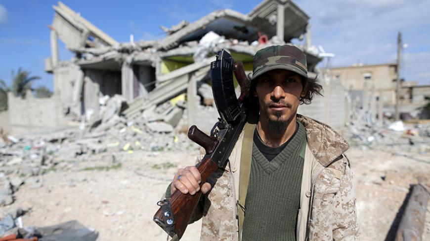 A member of East Libyan forces holds his weapon as he stands in front of a destroyed house in Ganfouda district in Benghazi, Libya, January 28, 2017. REUTERS/Esam Omran Al-Fetori - RTSXTD1