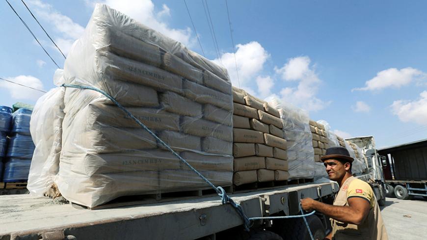 A Palestinian man stands next to a truck loaded with bags of cement at the Kerem Shalom crossing between Israel and southern Gaza Strip May 23, 2016. REUTERS/Ibraheem Abu Mustafa - RTSFJF6
