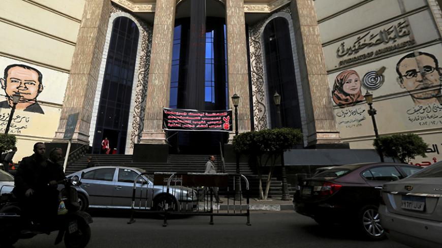 People and vehicles move past a black sign that reads "The press; It is not a crime" in front of the Egyptian Press Syndicate's headquarters in downtown Cairo, Egypt, November 20, 2016. REUTERS/Mohamed Abd El Ghany - RTSSGRD