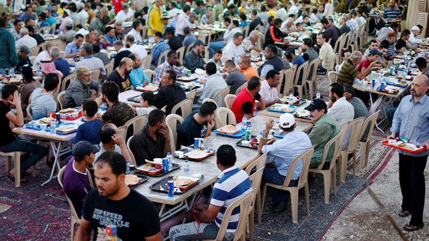 Muslim men eat iftar, or the evening meal, to break fast, at Tkiyet Um Ali, a humanitarian services center, in Amman, Jordan, June 15, 2016. REUTERS/Muhammad Hamed  - RTX2GGA9