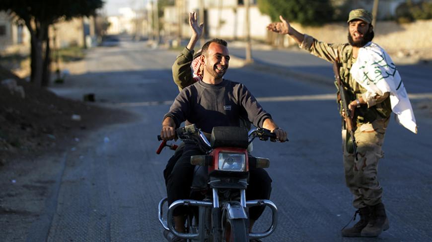 Residents driving a motorcycle gesture towards a fighter in Dabiq town, northern Aleppo countryside, Syria October 16, 2016. REUTERS/Khalil Ashawi   - RTX2P3YI