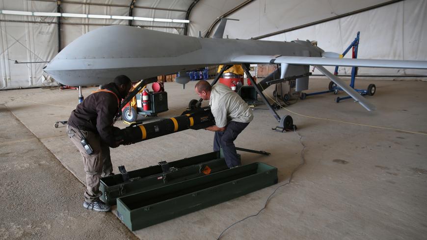 UNSPECIFIED, UNSPECIFIED - JANUARY 07:  Contract workers load a Hellfire missile onto a U.S. Air Force MQ-1B Predator unmanned aerial vehicle (UAV), at a secret air base in the Persian Gulf region on January 7, 2016. The U.S. military and coalition forces use the base, located in an undisclosed location, to launch drone airstrikes against ISIL in Iraq and Syria, as well as to distribute cargo and transport troops supporting Operation Inherent Resolve. The Predators at the base are operated and maintained by