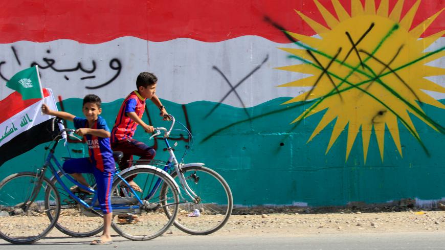 A boy drives a bicycle with an Iraqi flag in Dibis area on the outskirts of Kirkuk, Iraq October 17, 2017. REUTERS/Alaa Al-Marjani - RC1DD9EF0F10