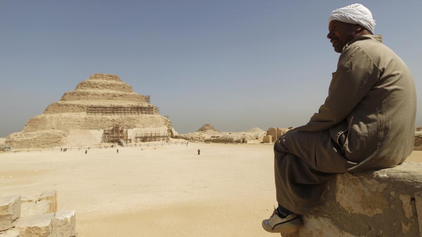 A guide sits on a stone as he looks at the Djoser's step pyramid in Saqqara, outside of Cairo March 5, 2011. Sites around the great pyramid at Giza, a Wonder of the Ancient World, the Sphinx and the cemetery at Sakkara have been nearly empty of tourists since a revolt started a month ago that ousted Hosni Mubarak and now Egypt wants visitors to return. REUTERS/Peter Andrews (EGYPT - Tags: CIVIL UNREST POLITICS TRAVEL SOCIETY) - GM1E7351JOK01