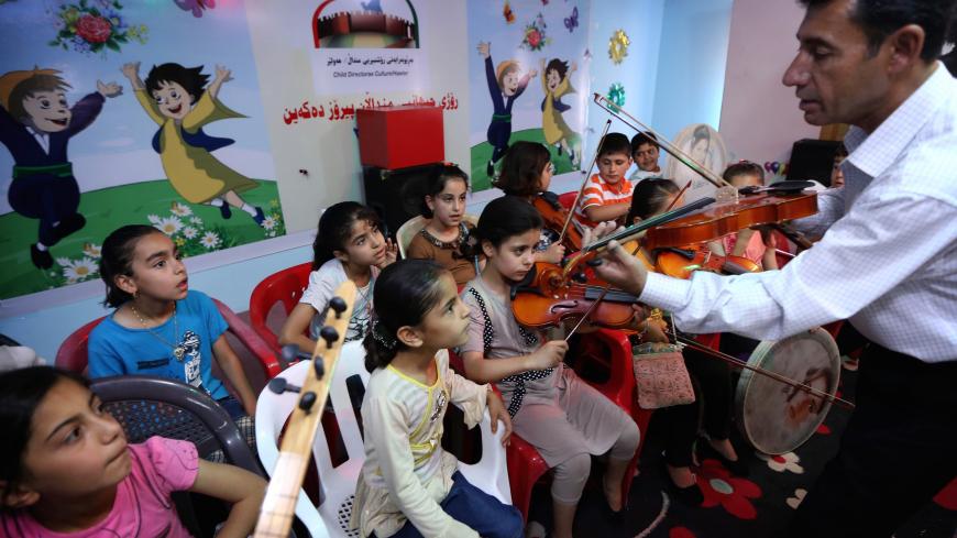 An Iraqi Kurdish music teacher gives a music lesson at a summer school in Arbil, the capital of the autonomous Kurdish region of northern Iraq, on June 17, 2014. The Kurdish region has been receiving displaced Iraqis fleeing nearby areas in northern Iraq taken over by militants, lead by jihadists from the Islamic State of Iraq and the Levant (ISIL), in a swift offensive in which they have said they intend to advance on Baghdad. AFP PHOTO/SAFIN HAMED        (Photo credit should read SAFIN HAMED/AFP via Getty