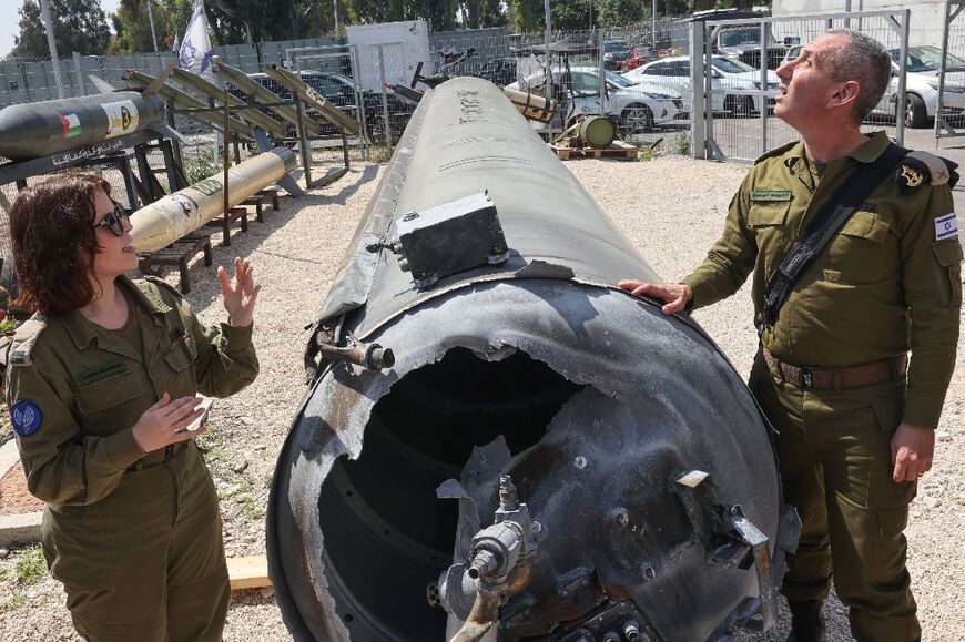 Israeli military spokesman Rear Admiral Daniel Hagari (R) and his deputy Masha Michelson stand next to an Iranian ballistic missile which fell in Israel at the weekend
