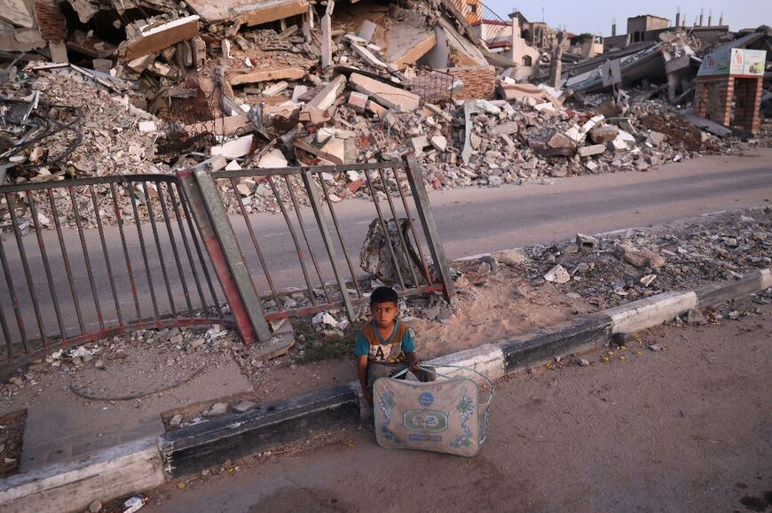 A Palestinian boy sits on a war-damaged road at al-Bureij refugee camp in the central Gaza Strip on June 26, 2024