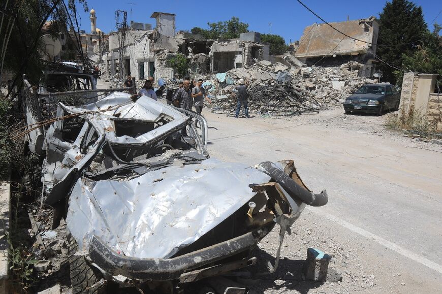 People walk past the rubble of a building that was destroyed by previous Israeli bombardment in the village of Yaroun in south Lebanon