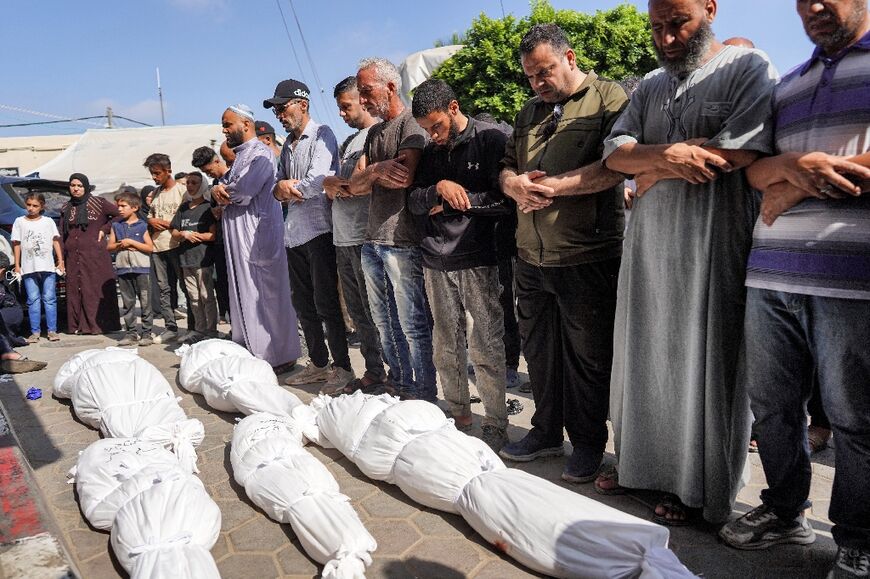 Men stand in prayer during the mass funeral of people killed, in the aftermath of overnight Israeli bombardment in al-Maghazi in the central Gaza Strip, outside the morgue of the Aqsa Martyrs hospital in Deir el-Balah on June 25, 2024