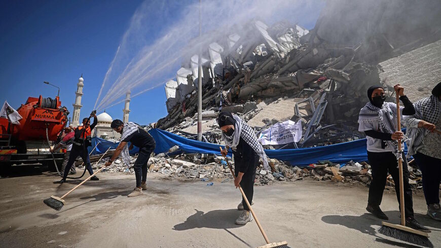 Palestinian volunteers and municipal workers clear the rubble of the Hanadi compound, recently destroyed by Israeli strikes, in Gaza City's Rimal district, on May 25, 2021. 