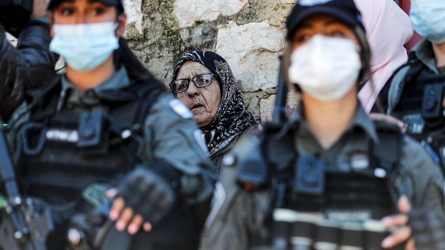 A Palestinian woman stands behind Israeli security forces in the east Jerusalem neighborhood of Sheikh Jarrah on February 13, 2022 