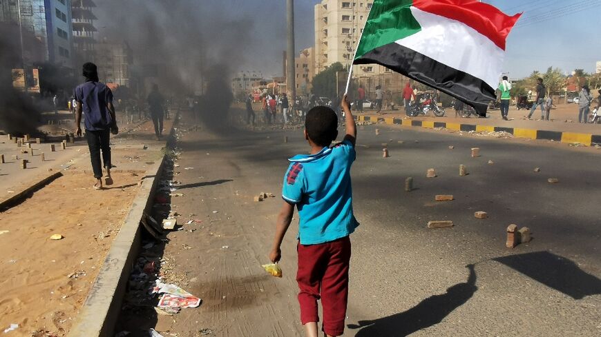 A young boy waves a Sudanese flag as protesters block a street in Khartoum on January 20