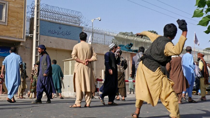 Afghan protesters throw stones at the Iranian consulate during a demonstration in Herat on April 11, 2022 after viral videos purportedly showed Afghan refugees being beaten by Iranians
