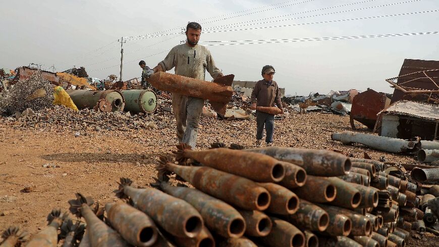 A Syrian family sorts unexploded ordnance at a metal scrapyard on the outskirts of Maaret Misrin town in the northwestern Idlib province, on March 10, 2021