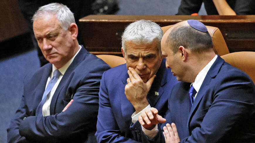 Israel's Defense Minister Benny Gantz looks on while Alternate Prime Minister and Foreign Minister Yair Lapid converses with Prime Minister Naftali Bennett as they are seated in the Knesset chamber after a special session to vote on a new government at the Knesset, Jerusalem, June 13, 2021.
