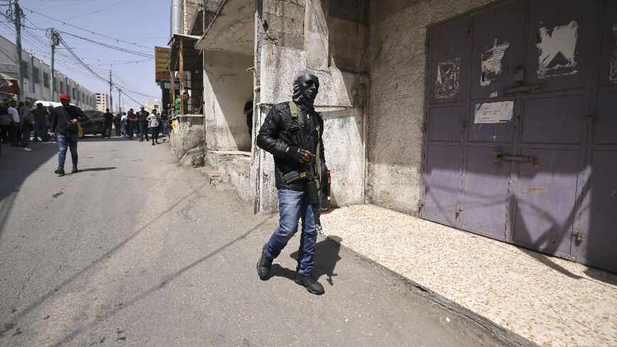 A masked militant parades his weapon at the funeral of a Palestinian killed by Palestinian fire during clashes with the Israeli army in the West Bank town of Al-Bireh