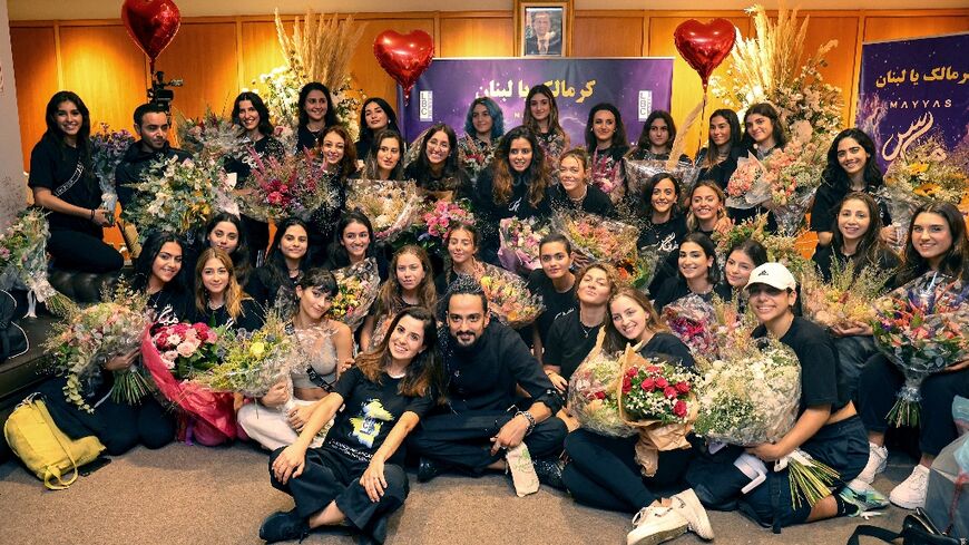 Members of the Lebanese dance group Mayyas pose for a group photo while surrounding their choreographer Nadim Cherfan (C) upon arrival at Beirut International Airport on September 16, 2022 after winning the "America's Got Talent" TV contest
