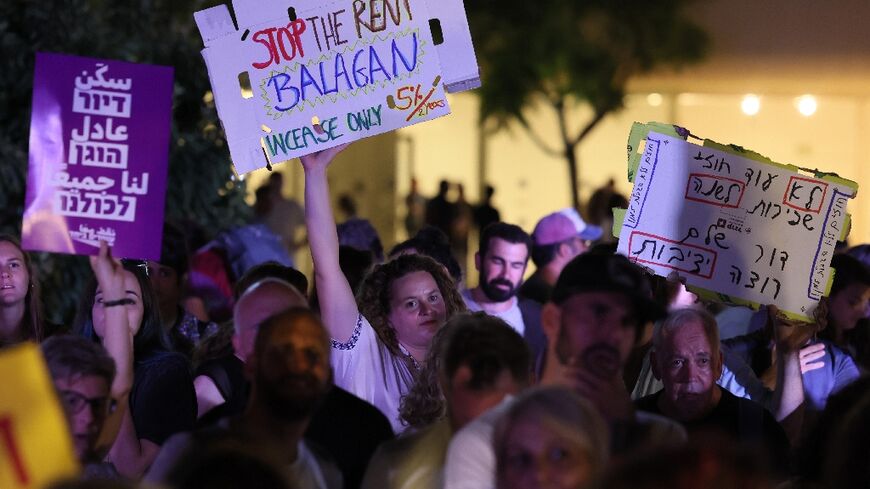 Israelis wave placards as they gather in the coastal city of Tel Aviv to demonstrate against the increase in prices in the real estate market on July 2, 2022