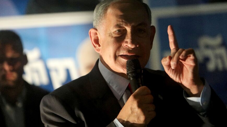 Israel's former prime minister Benjamin Netanyahu speaks to supporters from behind a security screen in the northern city of Tirat Carmel 