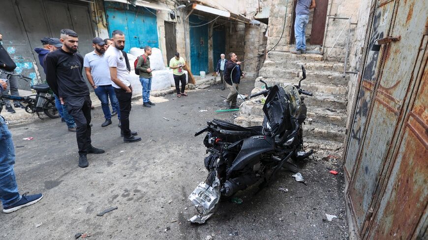Palestinians gather around a motorcycle, that was allegedly laden with explosives that killed Tamer al-Kilani