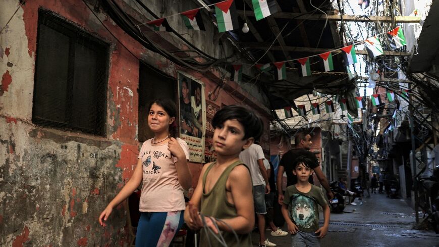 Children walk along a narrow alley beneath Palestinian flags  at the Shatila camp for Palestinian refugees in the southern suburbs of Lebanon's capital Beirut on September 9, 2022