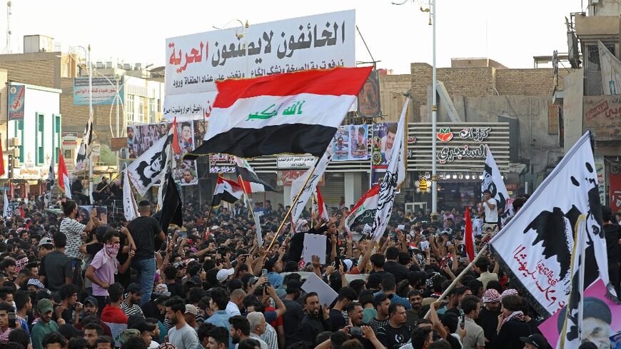 Iraqi protesters lift placards and national flags during a rally to mark three years since nationwide demonstrations erupted against endemic corruption, at al-Habboubi square in the southern city of Nasiriyah, on October 1