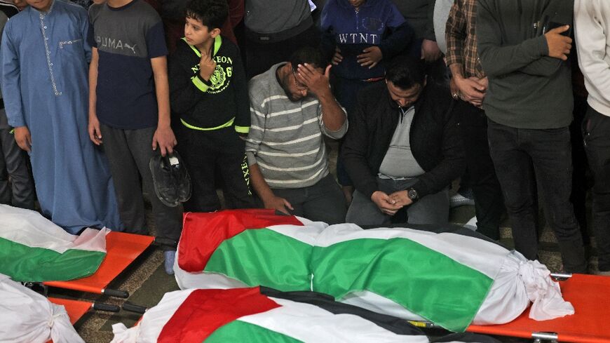 Palestinians mourn over the flag-draped bodies of those killed when a fire broke out in an apartment building in the Jabalia refugee camp in the northern Gaza strip