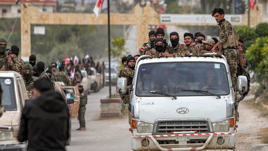 Syrian fighters ride in convoy during a military drill by a Turkish-backed faction in the opposition-held Afrin region in the north