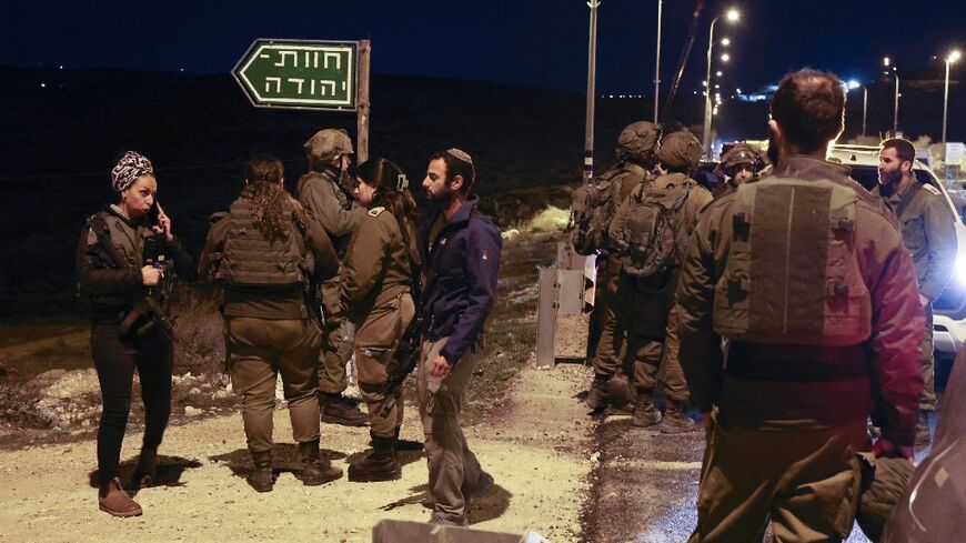 Israeli security forces and armed settlers gather near a settlement in the occupied West Bank after the stabbing attack 