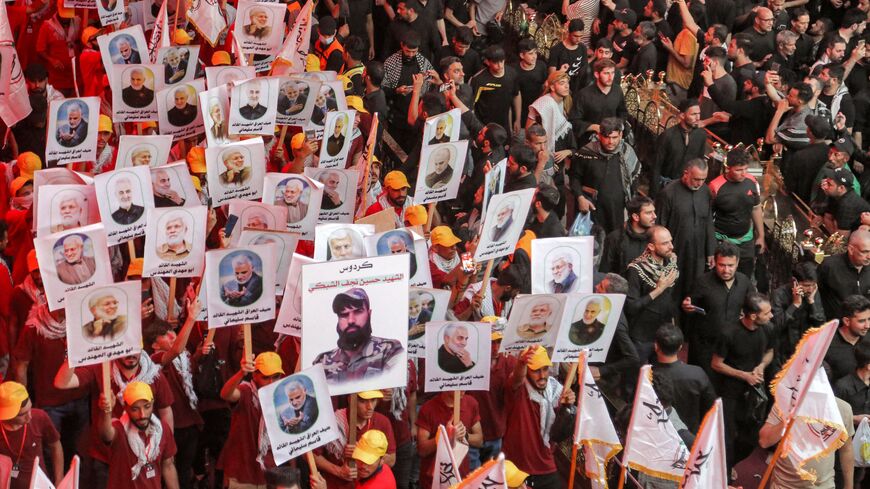 Iraq's Hashed al-Shaabi (Popular Mobilisation Forces) paramilitaries supporters raise pictures depicting their late slain commander Abu Mahdi al-Muhandis, and the slain top commander of the Iranian revolutionary guard corps (IRGC) Qasem Soleimani with whom he was killed in a US air strike, as they gather in Iraq's central holy shrine city of Karbala on September 16, 2022. (Photo by MOHAMMED SAWAF/AFP via Getty Images)