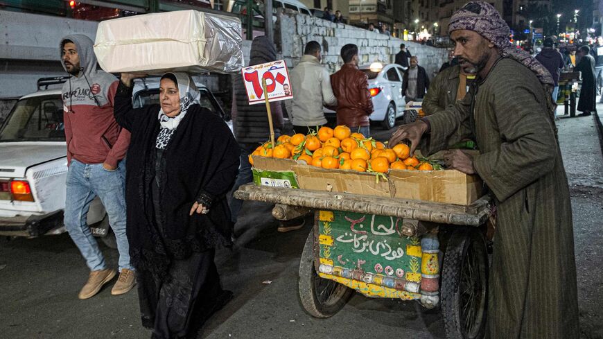 People walk past a pedlar selling tangerines along a street in the Azhar district of Egypt's capital Cairo on January 16, 2023. (Photo by Khaled DESOUKI / AFP) (Photo by KHALED DESOUKI/AFP via Getty Images)