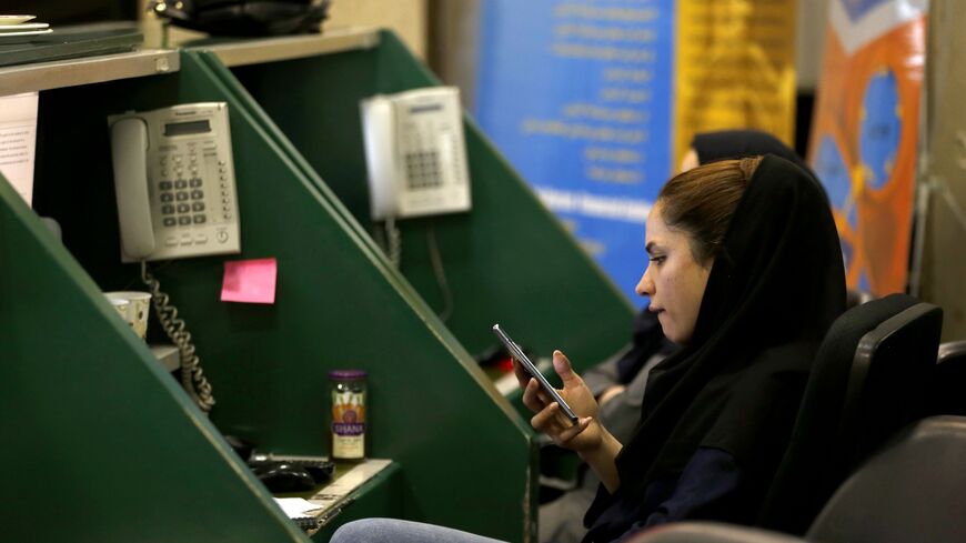 An Iranian dealer checks her phone at the stock exchange in the capital Tehran on May 8, 2018.