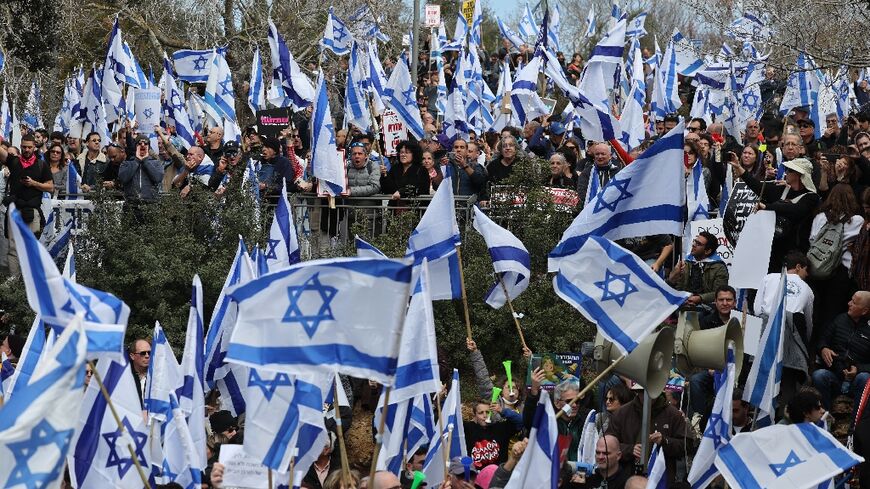 Israeli protesters wave national flags outside the parliament in Jerusalem against the controversial legal reforms being touted by the country's hard-right government