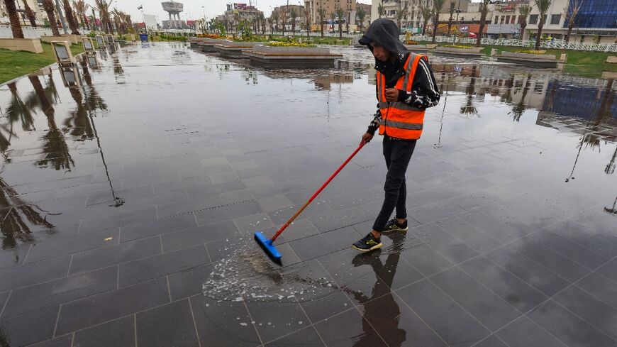 A municipal worker sweeps water from a public square in Baghdad after Wednesday's storm
