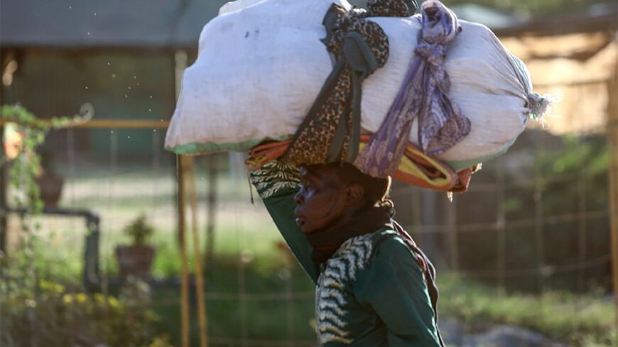 A woman carries her belongings as she flees amid fighting between the army and paramilitaries in Khartoum on April 19 