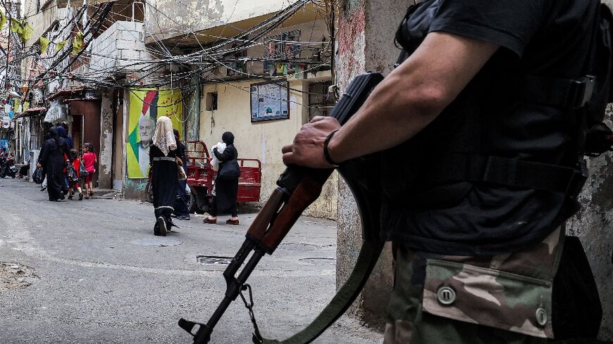 A fighter stands with an assault rifle in an alley of the Shatila camp for Palestinian refugees in the southern suburbs of Beirut