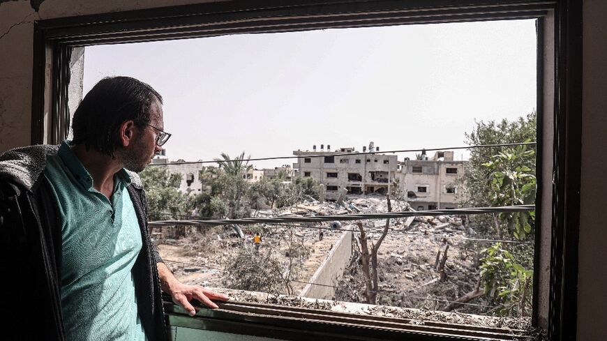 Mohammed Sarsour looks out from one of the windows of his damaged apartment in Deir al-Balah in the central Gaza Strip, days after it was hit by an Israeli air strike