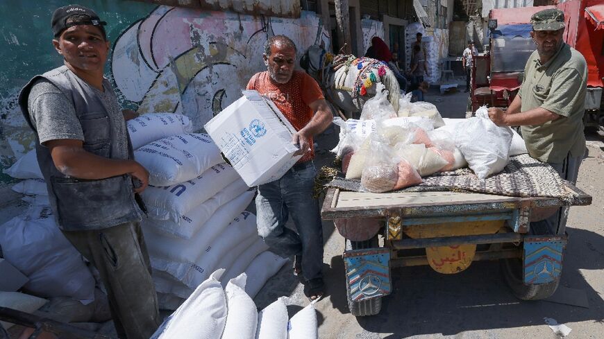 Palestinians carry bags of flour provided as aid to poor families from the United Nations Relief and Works Agency for Palestine Refugees (UNRWA) distribution center, at Al-Shati refugee camp in Gaza city 