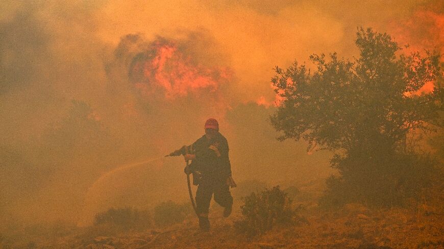 A firefighter tries to control a blaze in New Peramos, near Athens on July 19